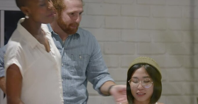 Diverse team collaborating at office, Asian woman surprised while holding smartphone