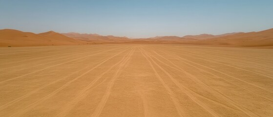 Fototapeta premium Desert landscape, sand dunes meeting the light sky with tire tracks stretching in parallel lines