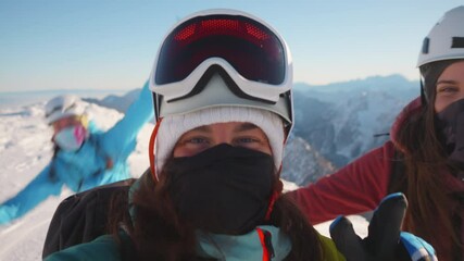 A close-up shot of two smiling women in ski gear on a snowy mountain, exuding joy and accomplishment.