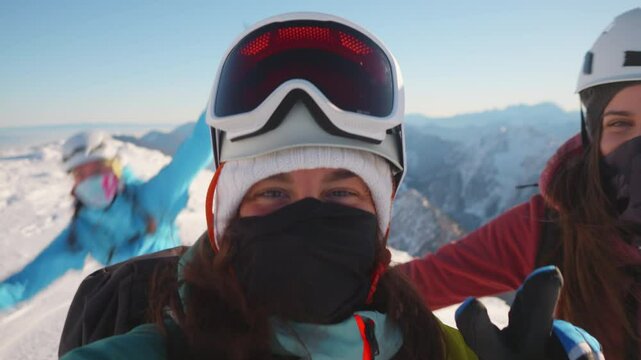 A close-up shot of two smiling women in ski gear on a snowy mountain, exuding joy and accomplishment.