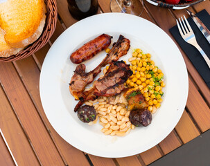 Delicious grilled meat served with chickpeas and beans on platter