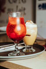 photo of sugar frosted mocktail with maraschino cherries and sparkling water in cafeteria, and next to it a chocolate milkshake