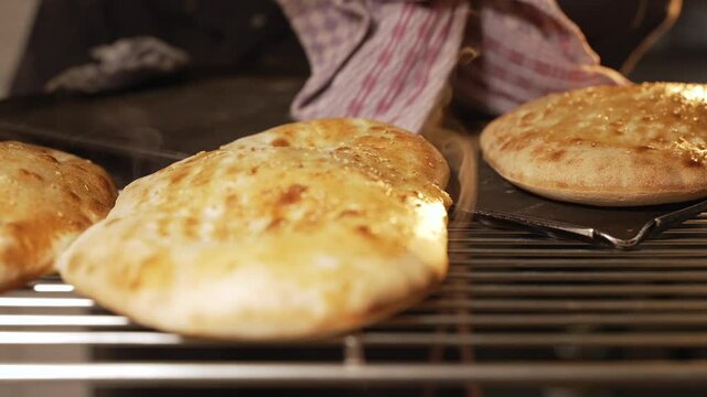 Man Putting freshly baked bread on a rack in a Kitchen. Rustic Smoking Caucasian Georgian bread. Restaurant Slow Motion 