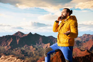 Trekker enjoys the high altitude landscape and making a phone call, panoramic mountain views and...