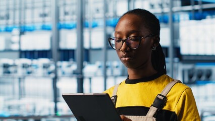 Smart factory engineer implements automated workflows and control systems using tablet, computerizing manual operations. Industry 4.0 worker integrates sensors into production using device, camera A