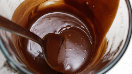 Close-up of a chocolate fudge in a glass measuring cup with a spoon