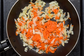 Frying finely chopped onions and carrots in a frying pan.
