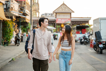 Fototapeta premium Young tourists couple walking in bangkok street market exploring thailand