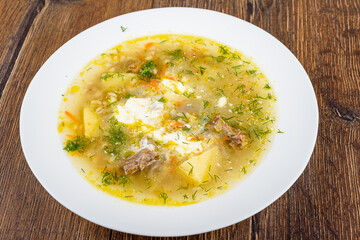 A plate of freshly prepared Leningrad-style rassolnik soup with added dill and sour cream.