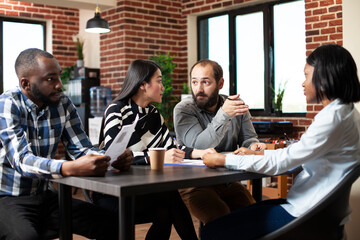 Diverse recruitment group evaluates potential female employee, exchanging questions about experience during job meeting. Asian woman and caucasian man sharing opinions about hiring young black woman.
