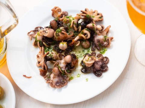Ready to serve baby octopus with greens on plate