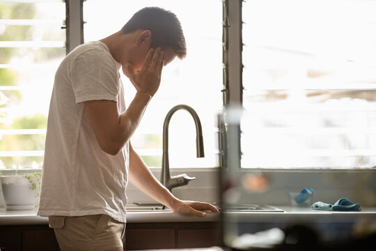 Closeup of young man touching temples with fingers as if suffering from severe migraine, headache, feeling sick at home