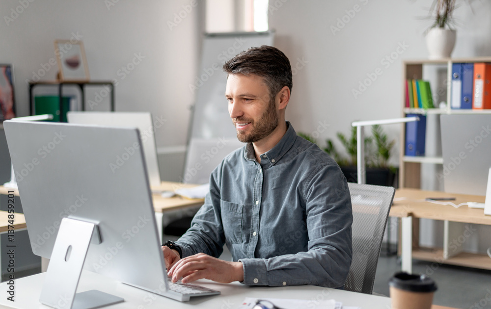 Poster cheerful middle aged businessman sitting at worktable at office, typing on computer keyboard, chatti