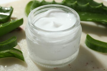 Cream and aloe leaves on light background, closeup
