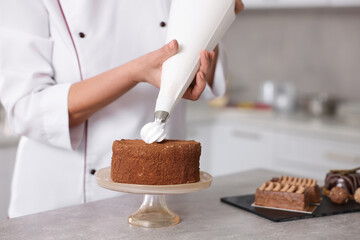 Professional pastry chef making cake at table in kitchen, closeup