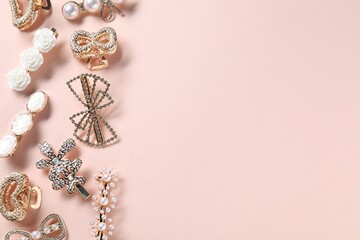 Different hair clips on pale pink background, flat lay. Space for text