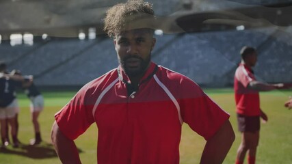 Rugby player in red jersey standing with teammates huddling on field - Powered by Adobe