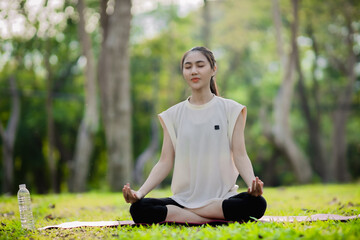 A enthusiastic Asian sports woman stopped after exercising at the garden, sitting on a exercise...