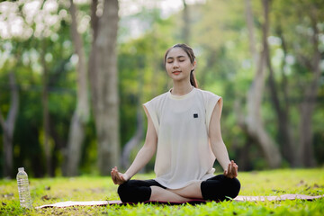 A enthusiastic Asian sports woman stopped after exercising at the garden, sitting on a exercise...