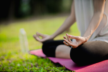 A enthusiastic Asian sports woman stopped after exercising at the garden, sitting on a exercise mat, inhaling deeply by closing her eyes. Sports and exercise regularly Health and health