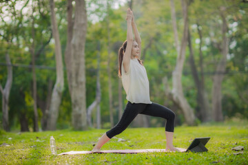 A enthusiastic Asian sports woman stopped after exercising at the garden, sitting on a exercise mat, inhaling deeply by closing her eyes. Sports and exercise regularly Health and health
