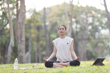 A enthusiastic Asian sports woman stopped after exercising at the garden, sitting on a exercise...