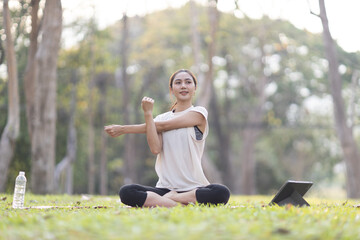 A enthusiastic Asian sports woman stopped after exercising at the garden, sitting on a exercise...