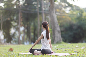 A enthusiastic Asian sports woman stopped after exercising at the garden, sitting on a exercise...