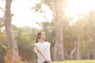 A enthusiastic Asian sports woman stopped after exercising at the garden, sitting on a exercise...