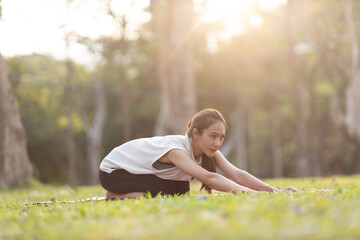 A enthusiastic Asian sports woman stopped after exercising at the garden, sitting on a exercise...