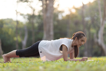 A enthusiastic Asian sports woman stopped after exercising at the garden, sitting on a exercise...
