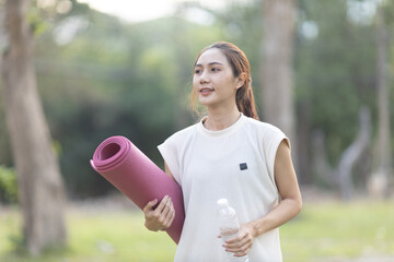 A enthusiastic Asian sports woman stopped after exercising at the garden, sitting on a exercise...