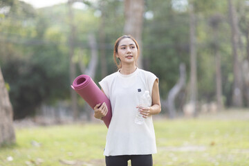 A enthusiastic Asian sports woman stopped after exercising at the garden, sitting on a exercise...