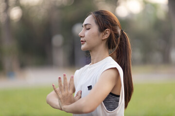 A enthusiastic Asian sports woman stopped after exercising at the garden, sitting on a exercise...