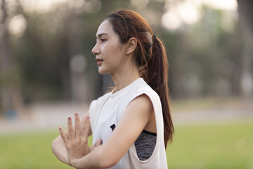 A enthusiastic Asian sports woman stopped after exercising at the garden, sitting on a exercise...