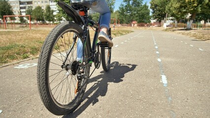 Fototapeta premium School girl riding a bicycle in a schoolyard on a sunny day, enjoying outdoor activity and exercise