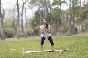 A enthusiastic Asian sports woman stopped after exercising at the garden, sitting on a exercise...