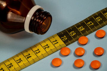 orange medicine pills with measuring tape and bottle. Weight loss idea