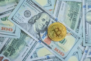 A Bitcoin token placed on America one hundred dollars banknote. Bitcoin is a digital currency which operates free of any central control or the oversight of banks or governments.