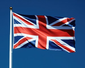 A vibrant British flag flutters gracefully against a clear blue sky, its bold red, white, and blue colors contrasting beautifully with the serene backdrop, symbolizing national pride.