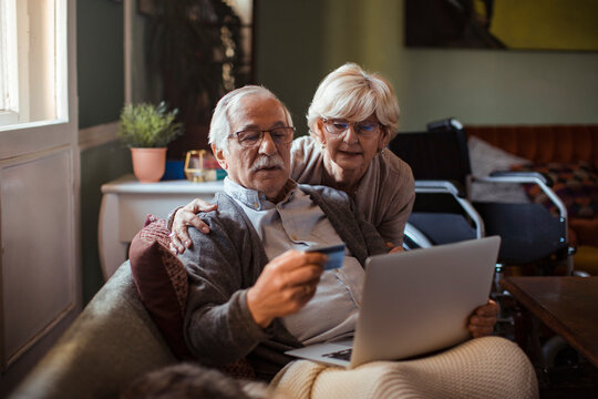Senior couple shopping online at home with credit card and laptop