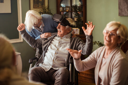 Senior man using virtual reality headset with friends and dog at home - Powered by Adobe