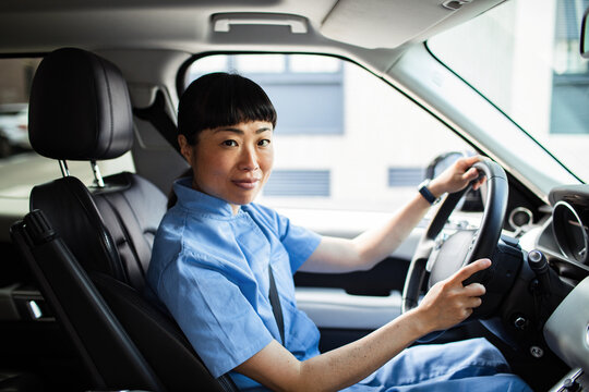 Portrait of a confident Asian nurse driving a car in uniform