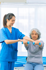 Obraz premium Elderly woman receives medical services from home care nurse while performing muscle strengthening exercises.