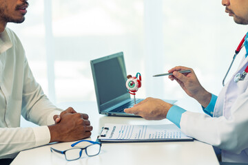 Young man consults doctor about eye disease at eyeball model on table