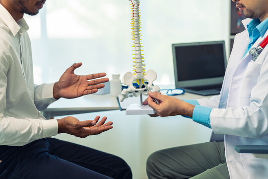 Professional orthopedic doctor is counseling a young man with spinal contour in hospital They talk about spinal problems, check up on health.