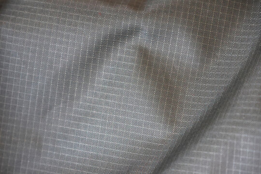 A close-up of a smooth, gray fabric with a tightly woven pattern. The material has a glossy finish and is likely used for outdoor gear such as jackets or backpacks due to its durability