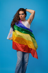 genderless person wrapped in a pride flag with a blue background and copy space