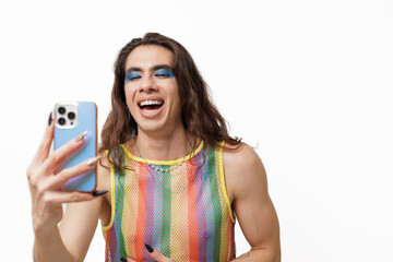 Genderqueer person takes a selfie wearing pride clothing, smiling and posing happily for the camera.