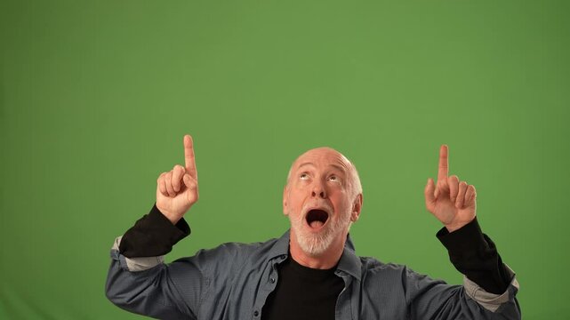 A mature man with gray hair enthusiastically gestures toward the ceiling, showcasing excitement against a green screen, ideal for product announcements or promotions.